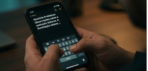 Recriação: mãos digitando um texto no aplicativo de notas de um iPhone, à noite.
