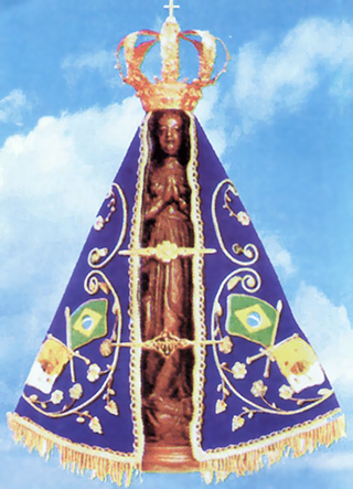 A imagem de Nossa Senhora Aparecida, de manto azul e coroa de ouro — capa da história de como se tornou padroeira do Brasil.